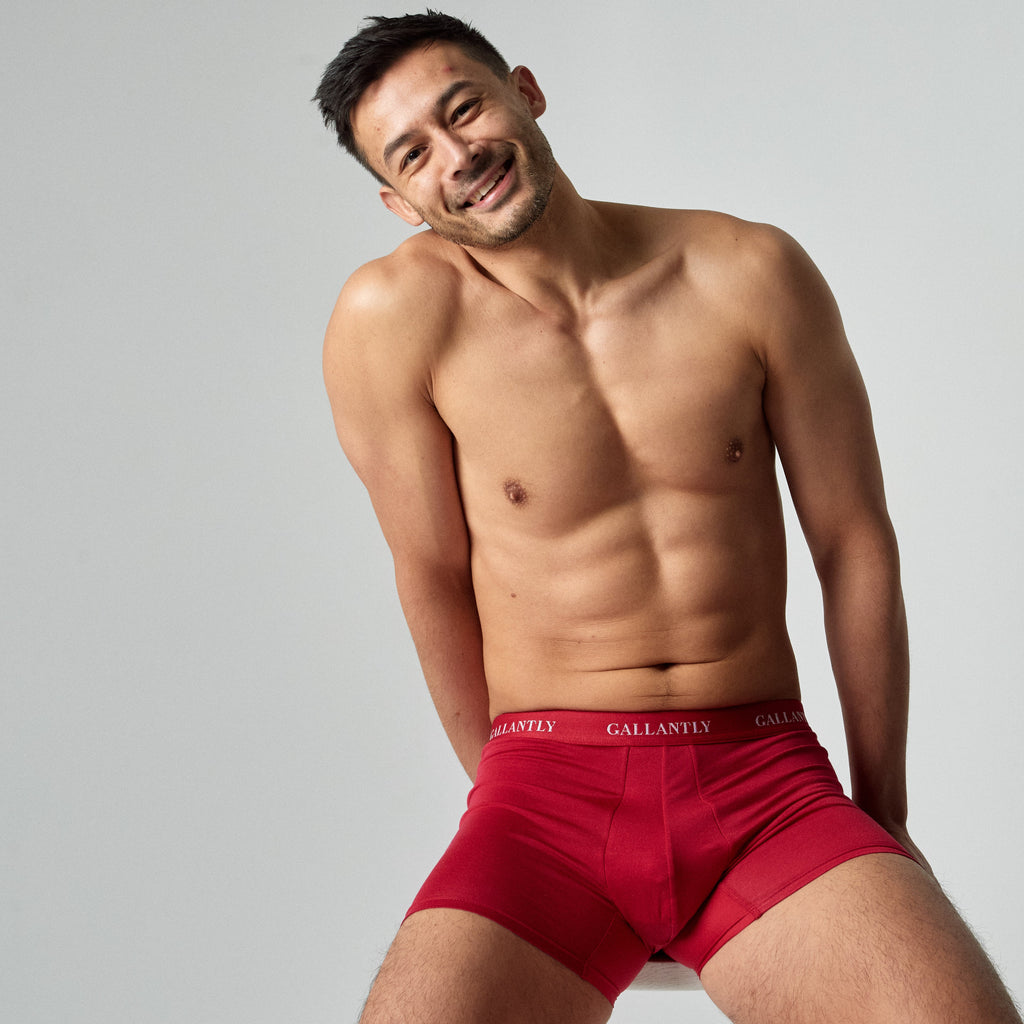 Man wearing red underwear with a visible brand logo on a plain background